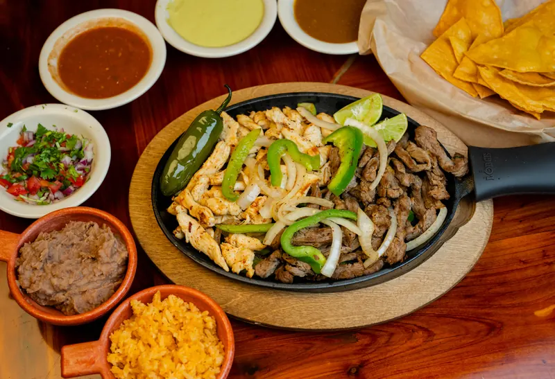 Sizzling chicken and steak fajitas with peppers and onions