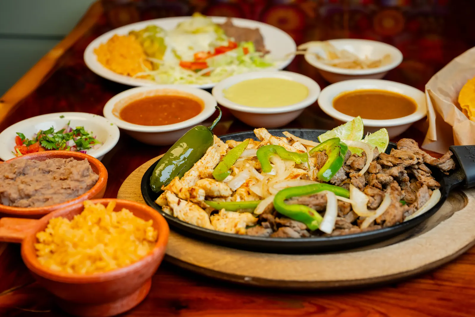 Chicken and steak fajitas with rice, beans, salsas, and pico de gallo